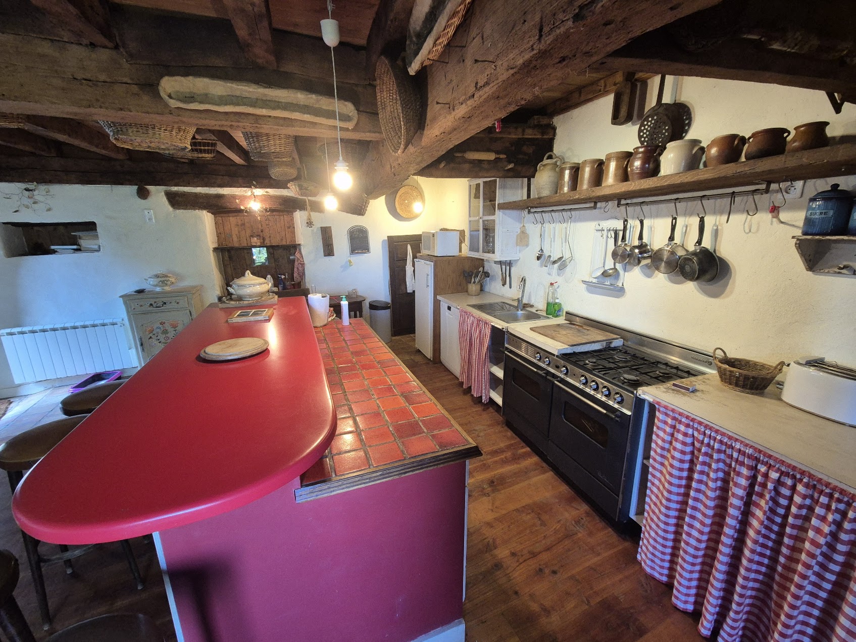 Cuisine conviviale avec comptoir rouge et poutres apparentes